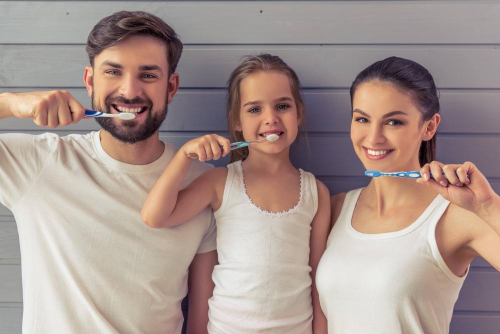 Mom, dad, and daughter brushing teeth
