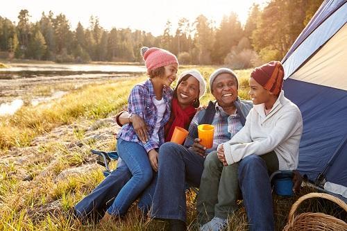 family of four laughing and smiling while camping