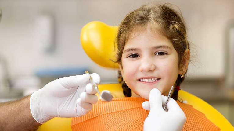 young girl smiling while sitting in dental chair