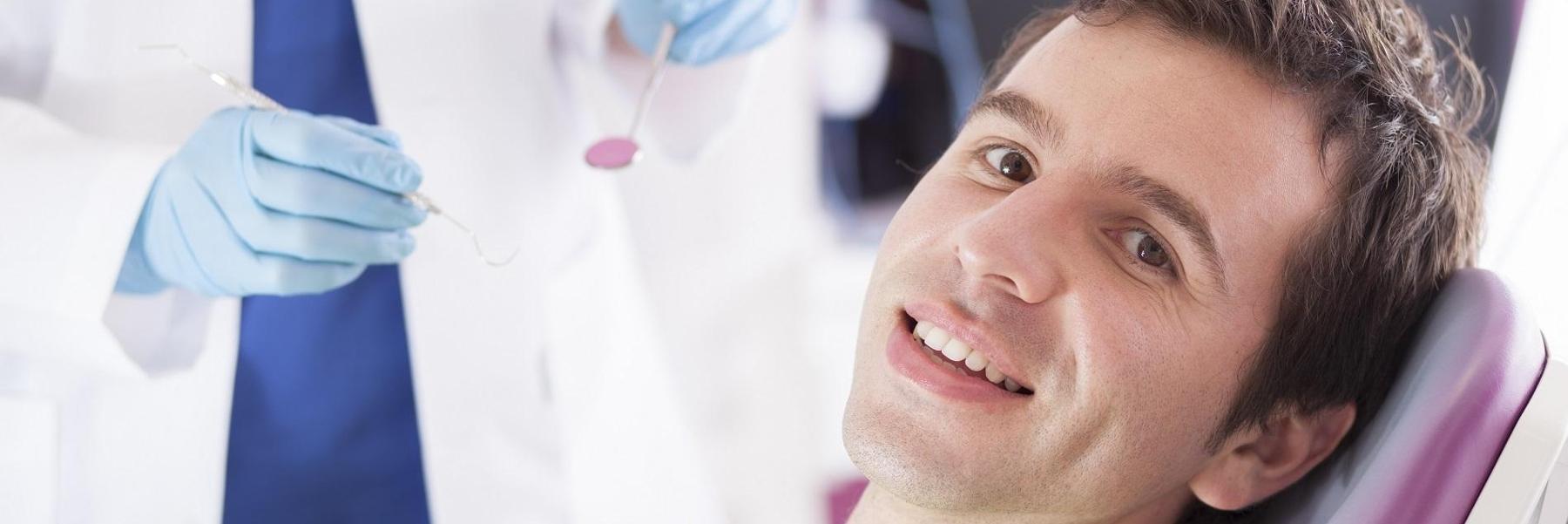 man sitting in dental chair after getting emergency dental care